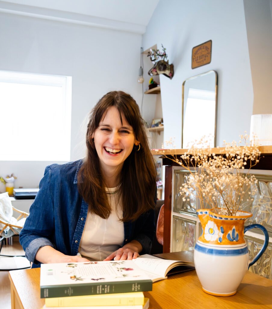 Camille, la fondatrice de Bonne Heure Studio, à son bureau en train de rire aux éclats
